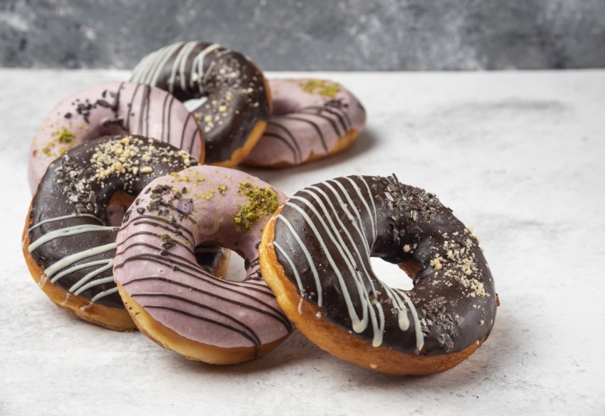 Glazed chocolate and pink donuts on marble background