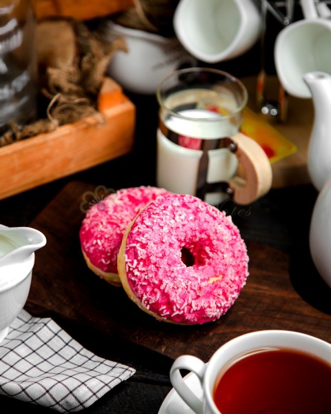 A pair of donuts with pink cream and candies
